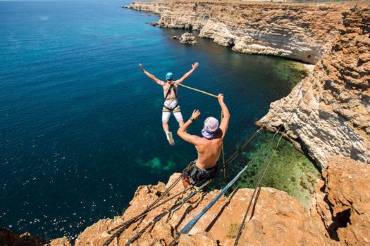 Rope jumping off a cliff with a rope in the water. The ocean. Sea. Mountain.