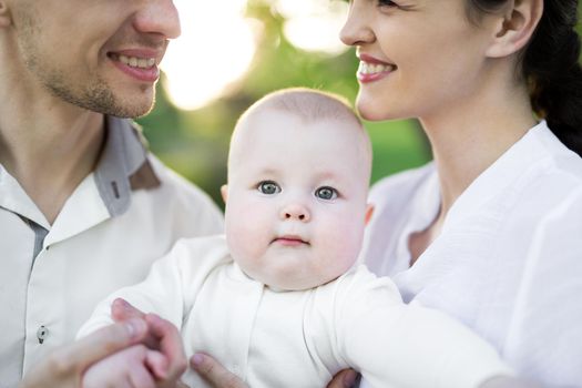 Portrait Beautiful Mother, Father And Baby outdoors. Happy family on a summer meadow