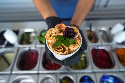 Stir-fried ice cream rolls at freeze pan. Rolled ice cream, hand made ice cream dessert. Fried ice cream machine with steel chilled pan.