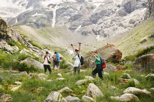 Women with backpacks and scandinavian sticks climb the mountains in Caucasus