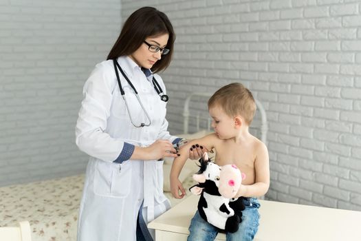 Doctor pediatrician giving child an intramuscular injection in arm