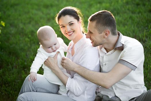 Portrait Beautiful Mother, Father And Baby outdoors. Happy family on a summer meadow