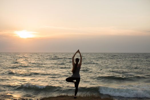 Caucasian woman practicing yoga at seashore of ocean