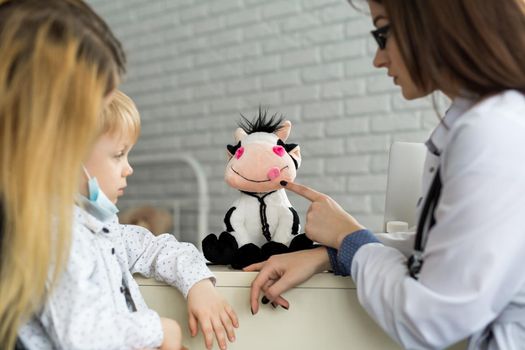 A boy playing doctor with a soft cow toy
