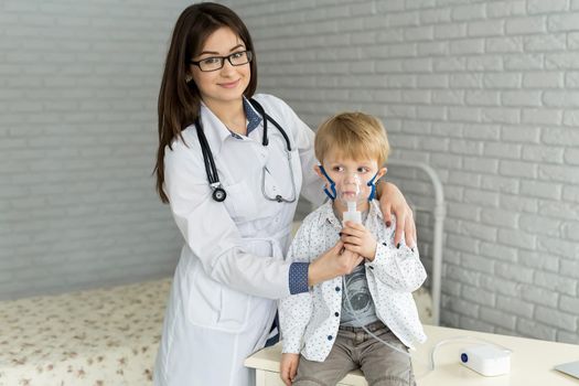 Medical doctor applying medicine inhalation treatment on a little boy with asthma inhalation therapy by the mask of inhaler.