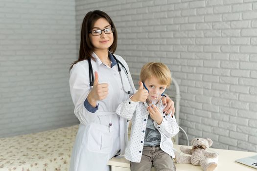 Medical doctor applying medicine inhalation treatment on a little boy with asthma inhalation therapy by the mask of inhaler.