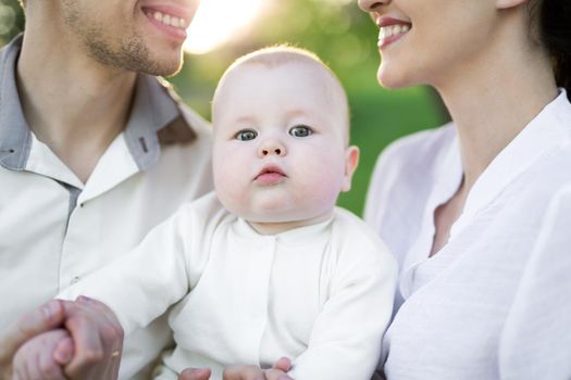 Portrait Beautiful Mother, Father And Baby outdoors. Happy family on a summer meadow