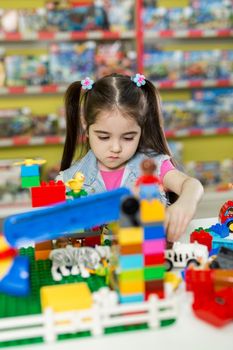 Little girl playing with building blocks in the store