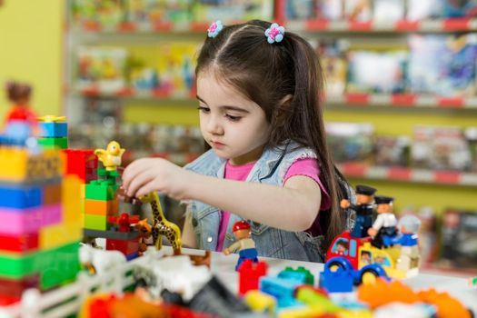 Little girl playing with building blocks in the store