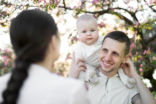 Happy man and woman playing with baby outdoors