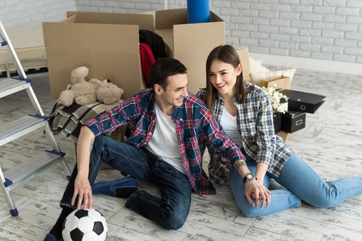 Young couple in a new home relaxing on the background of big boxes. Concept housewarming, began living together.