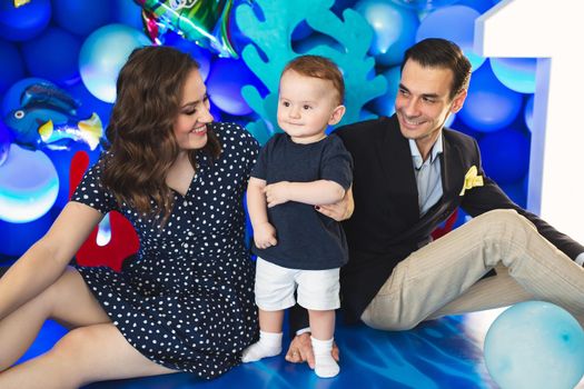 Father, mother and son on the background of blue decor in the marine style at the holiday.