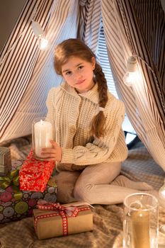 Beautiful little girl sitting with a burning candle in his hands. Christmas. New year. Studio