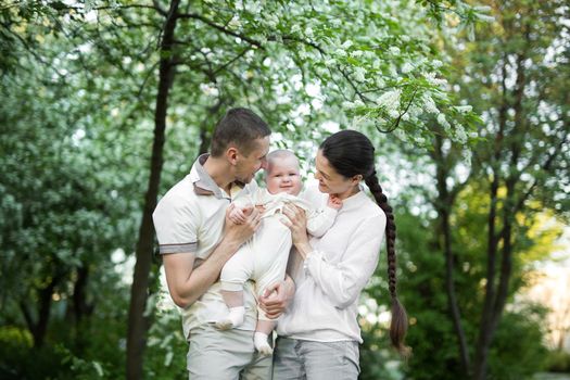 Portrait of a young family with a child. Happy young family spending time outdoor on a summer day. Happiness and harmony in family life. Happy family concept.