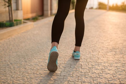 Athlete runner feet running on road closeup on shoe. woman fitness sunrise jog workout wellness concept.