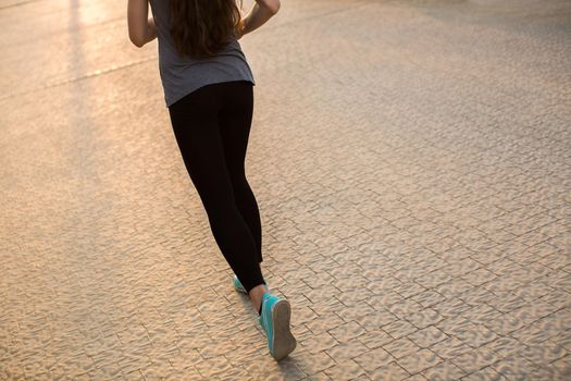 Athlete runner feet running on road closeup on shoe. woman fitness sunrise jog workout wellness concept.