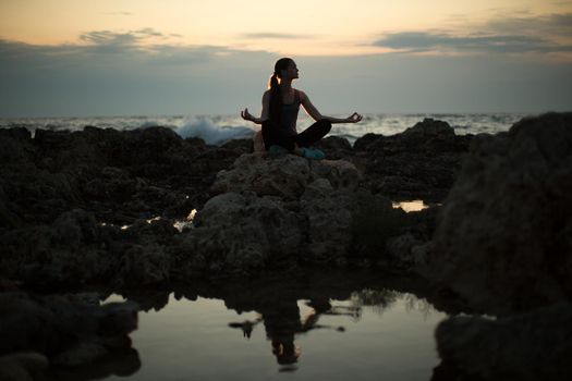 Caucasian woman practicing yoga at seashore of ocean