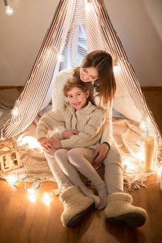 Beautiful mother and daughter, Christmas eve, sitting in the cosy interior. New year