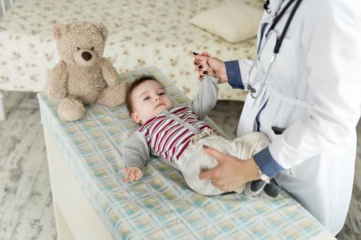 A pediatrician examining a baby on the bed