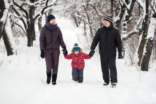 A young family with a child walking through a snow-covered forest