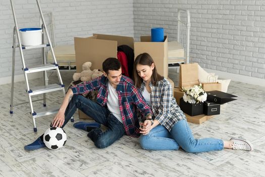 Young couple in a new home relaxing on the background of big boxes. Concept housewarming, began living together.