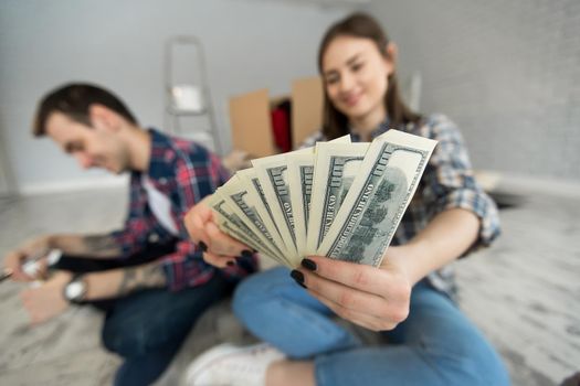 Young couple counting money while sitting on floor in new apartment