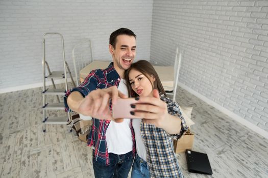 Young couple makes selfie while moving to a new apartment. Moving newlyweds to new housing.