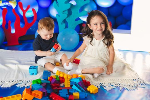 Two children, a boy and a girl, are sitting on the floor in the room, laughing, play