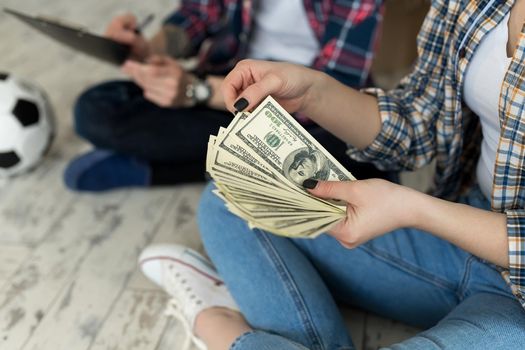 Young couple counting money while sitting on floor in new apartment