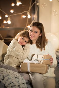 Beautiful mother and daughter opening a magical Christmas gift in the cozy interior of the house. New year