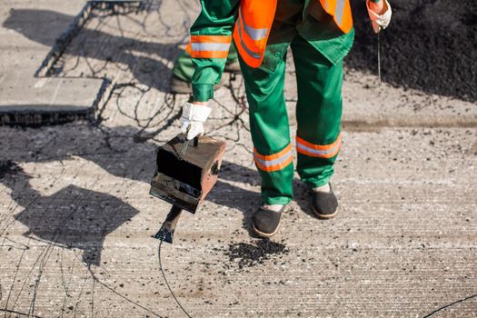 The man working asphalt pouring tar for road repair