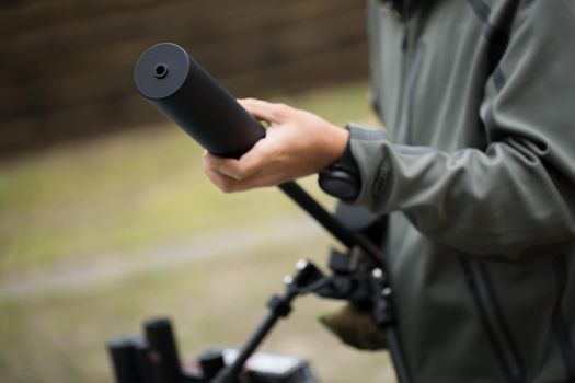 Military holds a pistol with a silencer.