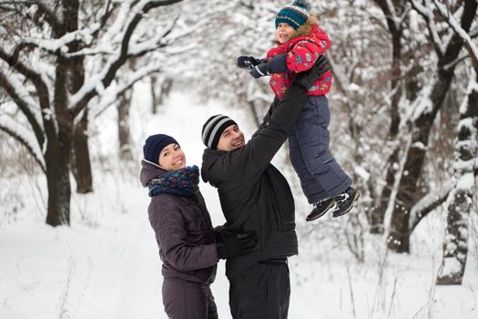 A young family with a child walking through a snow-covered forest