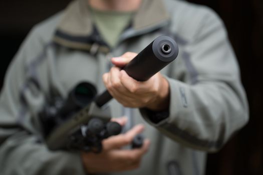 Military holds a pistol with a silencer.