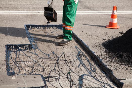 The man working asphalt pouring tar for road repair