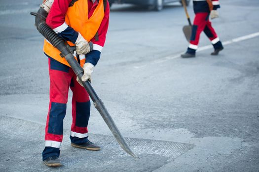 Worker with leaf-blower, cleaning out the dust for better asphalt adhesion, during tram track renewal works