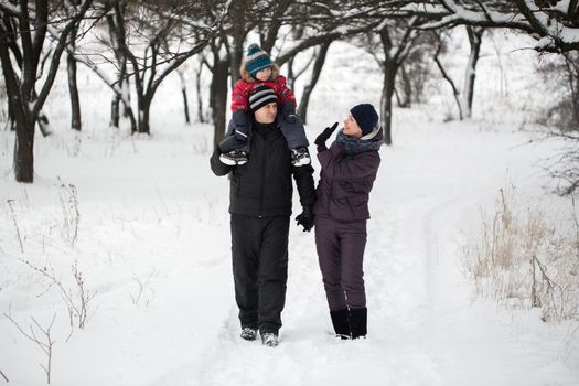 A young family with a child walking through a snow-covered forest