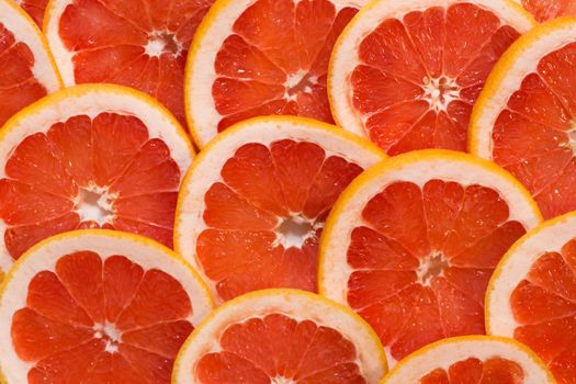 Bright red background with juicy slices of grapefruit. Healthy food background.