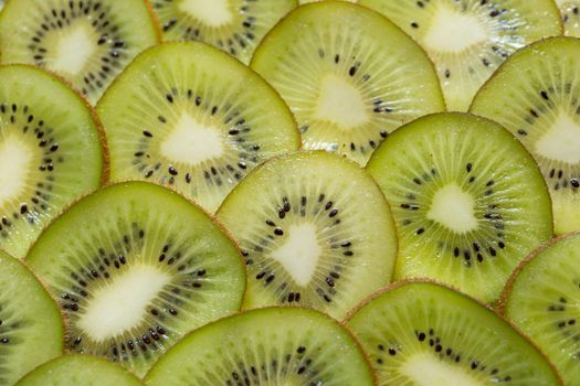 Bright green background with slices of juicy kiwi. Healthy food background.