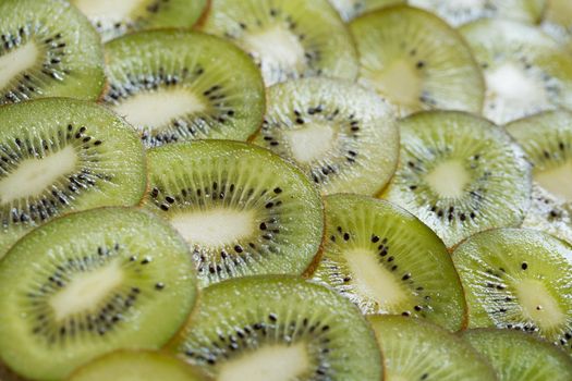 Bright green background with slices of juicy kiwi. Healthy food background.