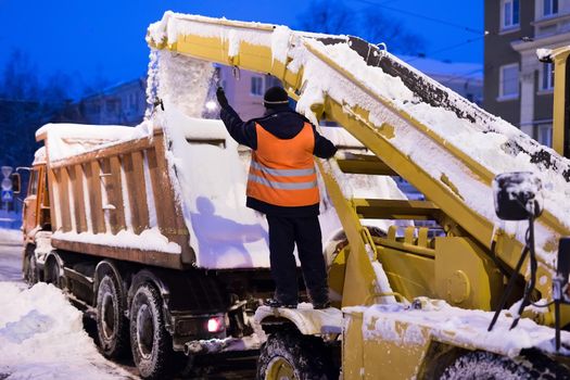 Claw loader vehicle removes snow from the road. Snow plow machine and snow truck clean the streets of snow in city
