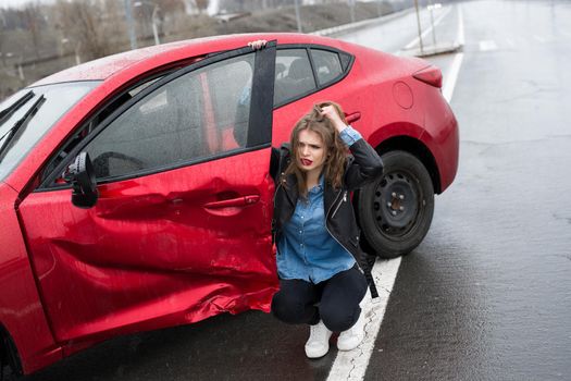 Woman sits near a broken car after an accident. call for help. car insurance