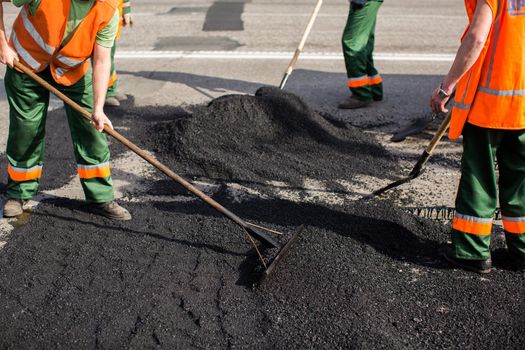 Workers on Asphalting paver machine during Road street repairing works. Street resurfacing. Fresh asphalt construction. Bad road