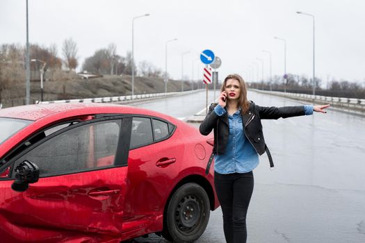 Woman calls to a service standing by a red car. Beautiful woman catches the car