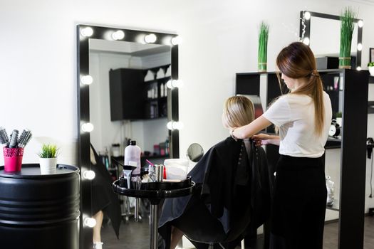Comb hair. The master in the hairdresser prepares the client's girl to restore the procedures