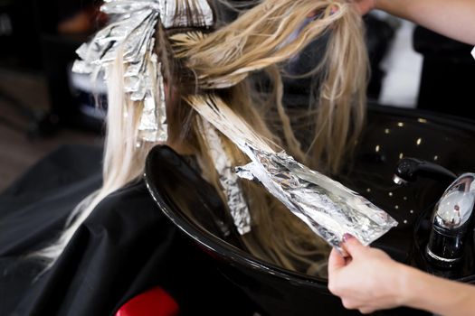 Stylist washes his head in a beauty salon. Hair color dying, foil