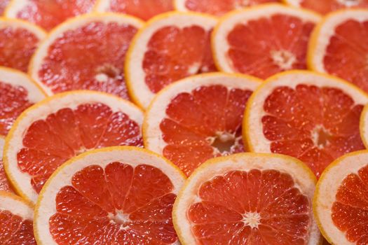 Bright red background with juicy slices of grapefruit. Healthy food background.