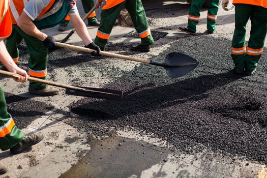 Workers on Asphalting paver machine during Road street repairing works. Street resurfacing. Fresh asphalt construction. Bad road