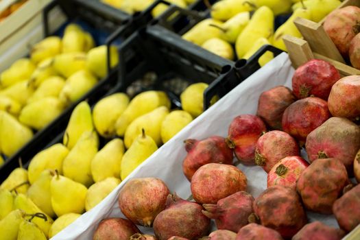 Counter with ripe pomegranates and pears in supermarket