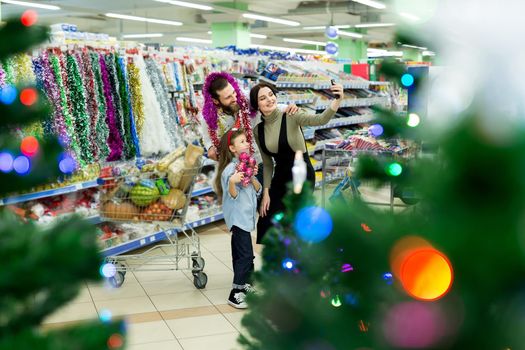 Happy young family in the supermarket chooses gifts for the new year. Family selfie